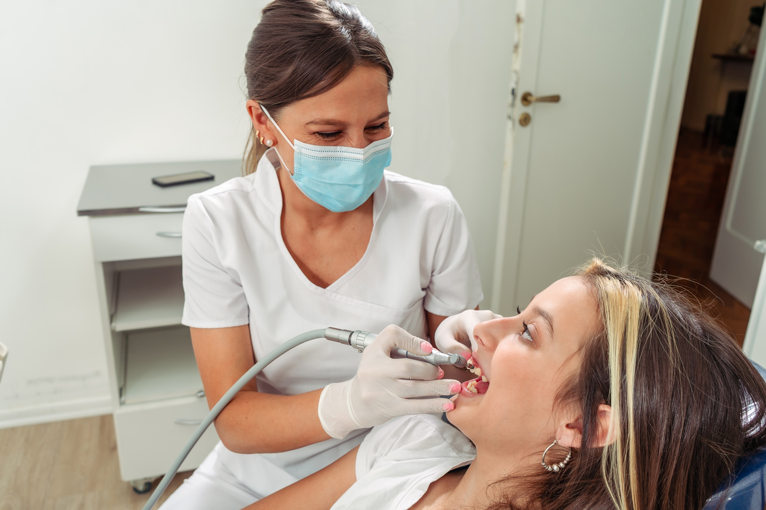 young Female dentist performing a lathe treatment on an adolescent patient. Concept dental care, health care.