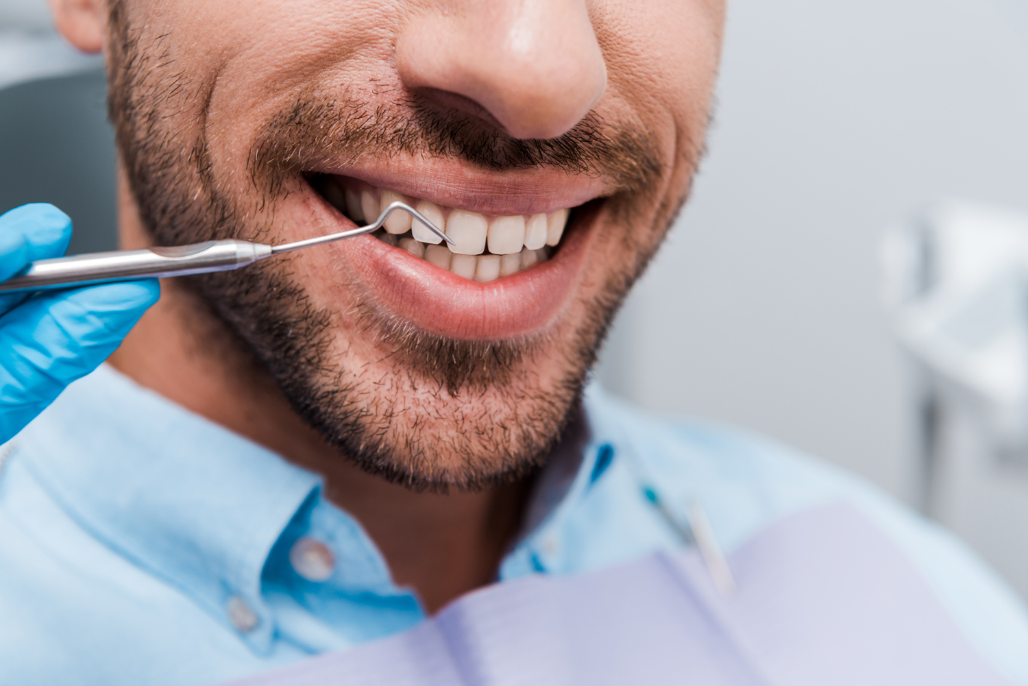 cropped view of dentist holding dental instrument near cheerful man